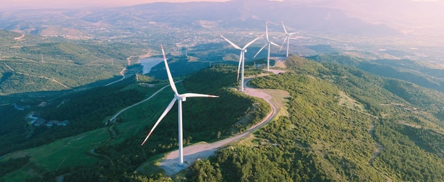 Turbiny wiatrowe położone na szczycie zielonego wzgórza.